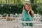 Outside shot of charming young woman with long hair, wears polka dot green shirt, sits at table in outdoor cafe, has pleasant talk