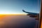 Outside the window`s airplan sunset seen with aircraft wing.