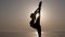 Outstanding womans silhouette. Front view of a girl stretching and practicing, Doing a vertical twine, bends her leg