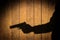 Outstretched arm with a gun. Black shadow on wooden background.