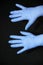 Outstretched blue gloved hands open, on black background