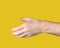 Outstretched male hand with open palm ready to shake other hand on yellow background. Gesture to reach out or take something.