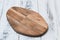 Oval cutting board on white wooden background side view