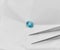 Oval Faceted Blue Zircon Gemstone with Tweezers in Parcel Paper Background
