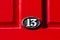 Oval number 13 on a bright red wooden front door