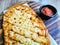 Oval Shape Cheesy Flatbread with Salsa Dip on a Round Wooden Pizza Board with Handle on a Wooden Table