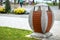 An oval-shaped garbage can on a concrete stand .