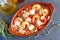 Oven backed prawns with feta, tomato, paprika, thyme in a traditional ceramic form on a abstract background. Healthy eating concep