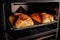 oven bake loaves of bread, with oven door open and heat escaping