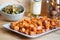 Oven baked sweet potato chunks on a plate with a bowl of vegetables