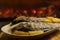 oven grilled sea bream fish with delicious curry sauce served on baking tray, baked potatoes with champignon mushrooms, spices,