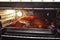 Oven with lighting, open for inspection the degree of readiness of the Christmas goose in baking tray, fried to ruddy crust,