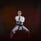 Over dark background an adult athlete in karategi trains formal karate exercises