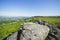 Over huge gritstone boulders and along the top of Baslow Edge to a distant, hazy Curbar Edge