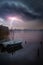 Over the lake with a rowing boat rages a thunderstorm with lightnings