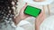 Over shoulder closeup view of girl holding smartphone green mockup screen.