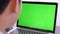 Over the shoulder shot of Asian boy looking at green screen. Office person using laptop computer with laptop green screen,