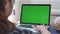 Over the shoulder shot of Asian woman looking at green screen. Office person using laptop computer with laptop green screen, 4K do