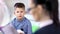 Over the shoulder shot young European boy answering for questions of female child psychologist