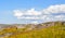 Over stones, hills and grass smoothly move huge white clouds