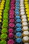 Over three dozen brightly colored cupcakes in vertical rows