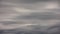 overcast gray clouds flowing horizontally just above horizon - telephoto view time-lapse