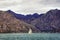 Overcast Mediterranean landscape. Sailboat sails alongs the shore of Kotor Bay, Montenegro