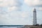 Overcast weather concept white lighthouse on edge of the world near stormy sea with waves on cloudy sky backdrop with copy space