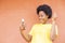 Overexcited African-American female with afro hair using a modern smartphone checking social media