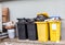 Overflowing plastic waste cans with garbage bags, cardboard boxes and a container with a liquid