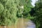 Overhanging rocks over calm river in canyon at summer day