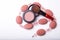 Overhead close up of one open jar of spilled pink blush powder with thick tipped brush on a white background