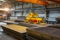 Overhead crane with electromagnetic beam grippers lifting steel sheets