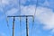 Overhead electrical power lines on old wooden pillars against the blue sky