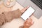 Overhead, Female in cozy sweater using smartphone at her minimal office desk