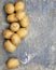Overhead, flat lay photo of several Yukon Gold potatoes scattered down the left side of a stained and scarred steel background.