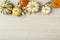 Overhead, horizontal flat lay still life of assorted orange and white pumpkins and ornamental squash on white wood background