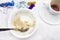 An overhead photo of dirty plate with porridge leftovers, chocolate candies wrapper, spoon and a cup of black espresso coffe.