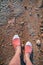 Overhead photo of feet on a background of brown sand. Women feets view from above. Exploring, travelling, tourism, leisure.