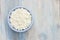 An overhead photo of fresh natural cottage cheese in a blue ceramic bowl on the wooden table. Organic eco healthy meal, dairy