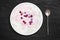 An overhead photo of fresh natural cottage cheese with cranberry yogurt in a white ceramic bowl on the black stone desk. Organic