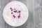 An overhead photo of fresh natural cottage cheese with cranberry yogurt in a white ceramic bowl on the wooden table. Organic eco