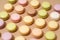 overhead shot of a beige table surface featuring an array of colorful macarons in neat rows