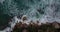 Overhead shot of The bluish ocean waves crashing against the rocks