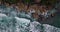 Overhead shot of The bluish ocean waves crashing the rock