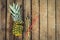 Overhead shot of a cocktail in a fresh pineapple fruit with a swizzle stick on the rustic wooden background