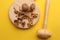 Overhead shot of crushed walnuts and shells next to a wooden mallet on a yellow background