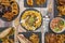 Overhead shot of fast food dishes, classic appetizers, tex mex food and in the center a plate of nachos with guacamole on a wooden