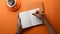 Overhead shot of female holding pen writing on notebook  on orange background.