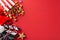 Overhead shot of film clapper, delectable popcorn in striped box, Santa\\\'s hat, festive ornaments, star decor on red backdrop